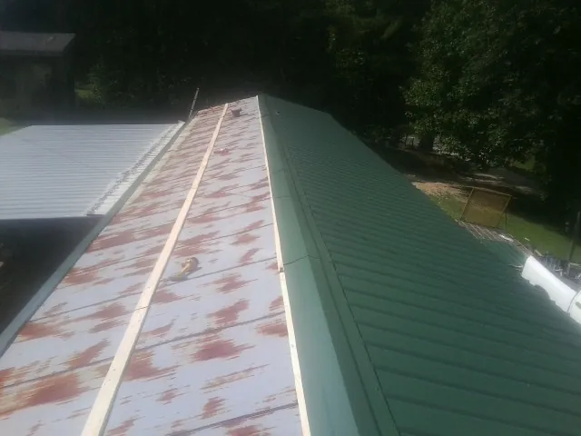 Old rusted panels beside newly installed green metal roofing — Wind Damage Roof Repair by Roofing Brothers in Scio