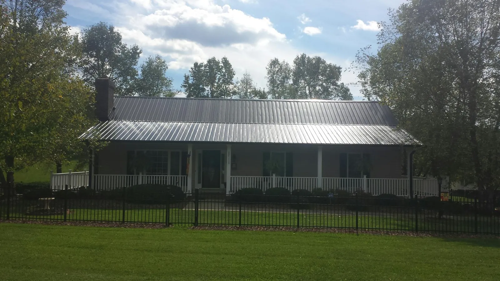 Gray metal roof on a brick ranch with a full width front porch — Gutter Guard Installation work by our crew in Scio