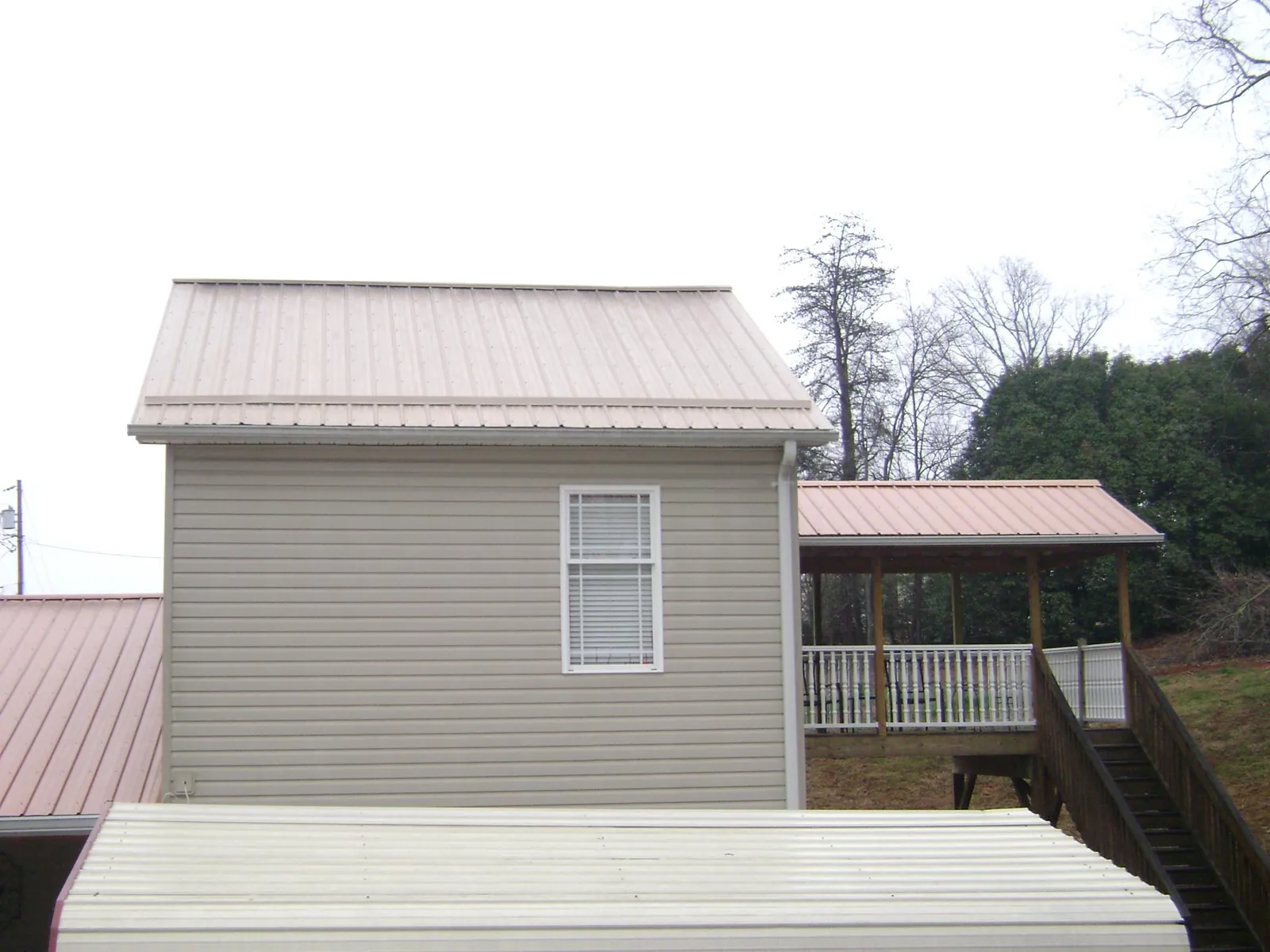 Tan metal roofs on a two story addition and attached porch, from a Roof Replacement job in Scio
